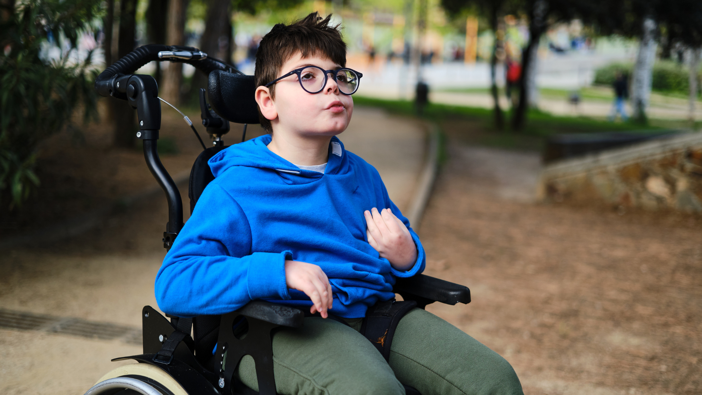 Ein Junge im Rollstuhl, der durch einen Park fährt 